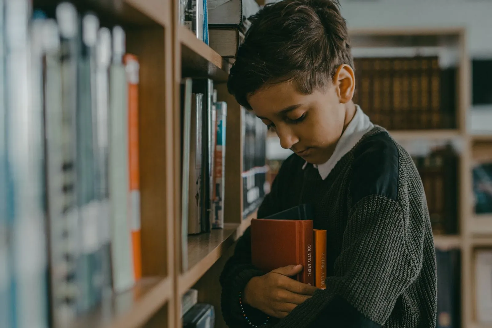 Young boy immersed in books at a cozy library, embracing learning.